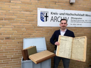 Stadtarchivar Jannick Stöber mit den Originalausgaben der Mescheder Zeitung. Foto: Stadt Meschede